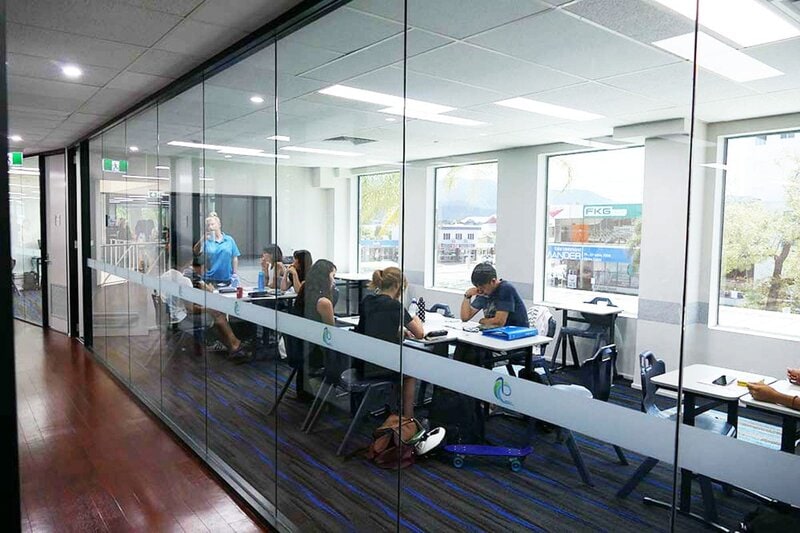Modernes Klassenzimmer mit Glaswänden, engagierten Studierenden und interaktivem Unterricht in einer hellen Lernumgebung.