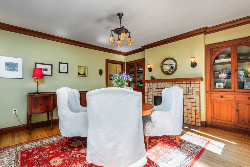 Close-up of the formal dining area of North Park Spanish style revival home showcasing original gumwood built-in cabinetry, a classic fireplace, and hardwood floors in the heart of this North Park home.