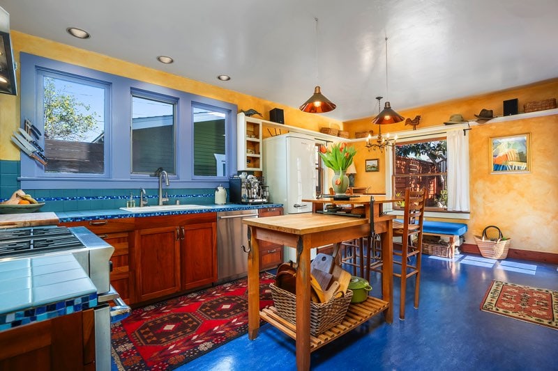 The heart of the home at 3237-39 Dale St featuring a large center prep island, custom wood cabinetry, blue tiled counters, and a bright breakfast nook.
