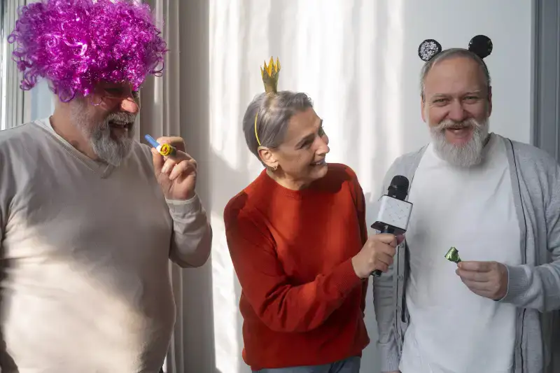 Three people celebrate with festive hats and party props, while one person conducts an interview using a microphone. The scene captures a joyful atmosphere, perfect for a celebration or event.