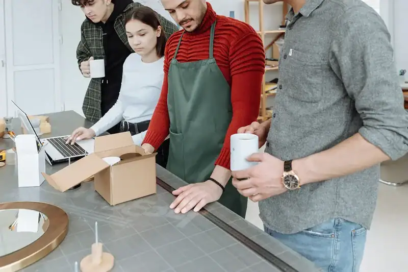 Team arbeitet an Produktverpackungen und Gestaltungselementen an einem Arbeitstisch.
