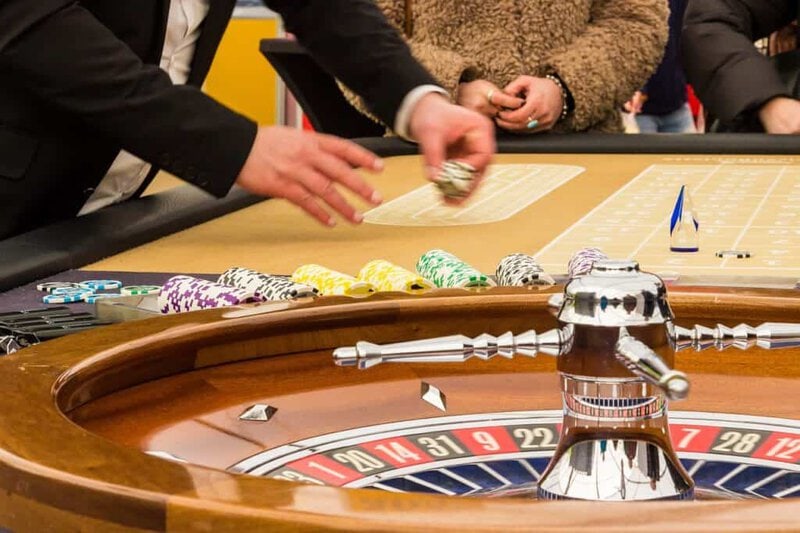 Casino roulette game with chips and croupier at a lively gaming table.