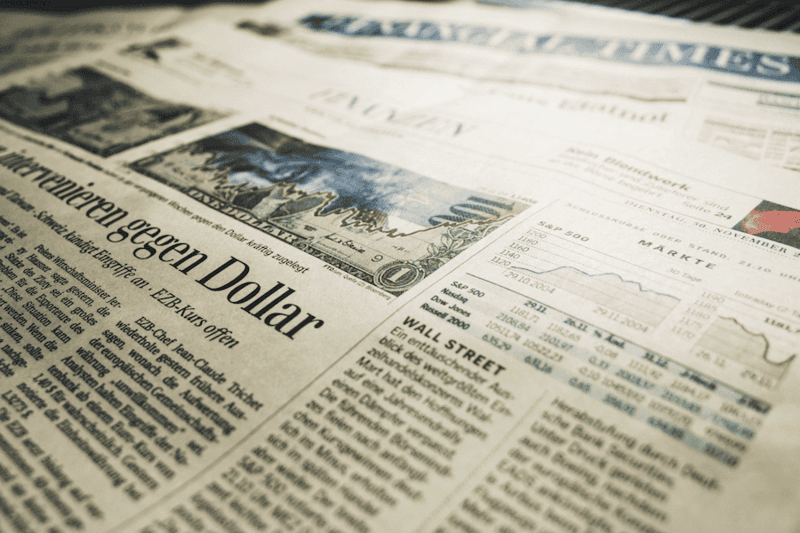 Financial newspaper with stock market and economic news headlines.