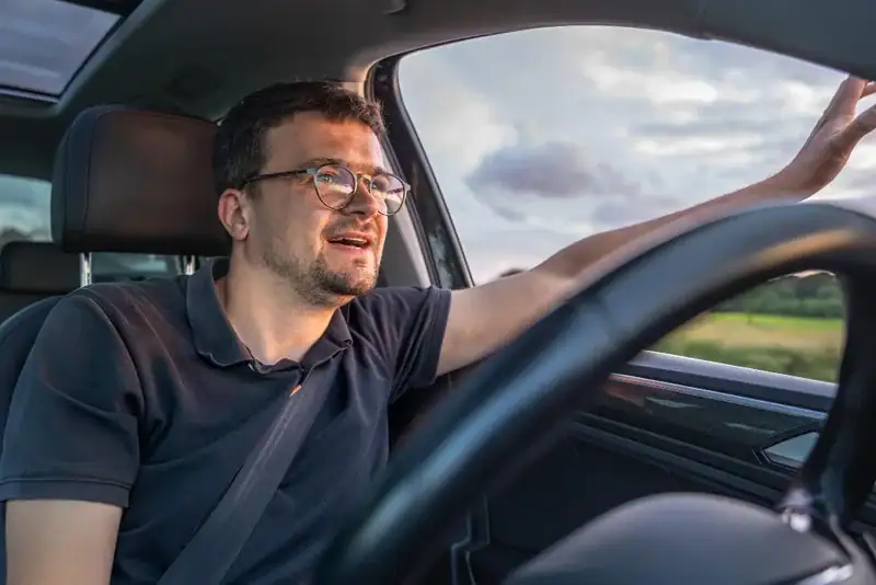 Homem dirigindo carro com cinto de segurança e olhando para fora da janela em dia nublado. Conteúdo sobre free flow na serra gaúcha