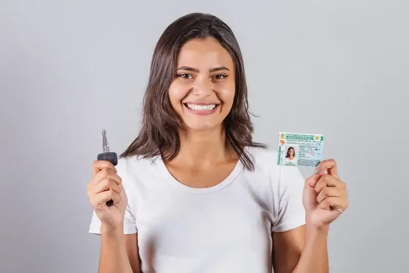 mulher sorridente segurando chave de carro e carteira de motorista brasileira. Conteúdo sobre renovação da carteira de motorista