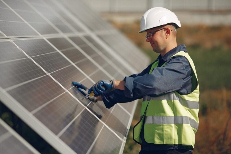 Técnico con casco y gafas de protección ajustando panel solar fotovoltaico, instalación de IELO