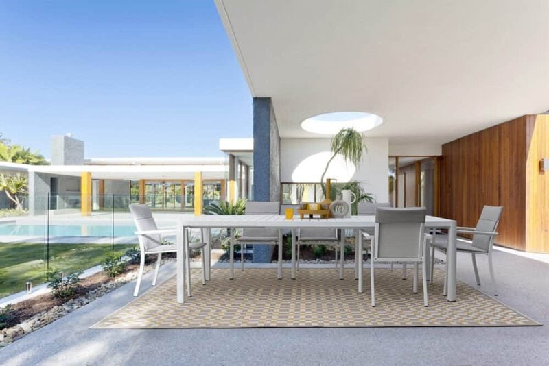Ampio spazio esterno con veranda, mobili di design e piscina, ideale per relax e convivialità all'aperto.
