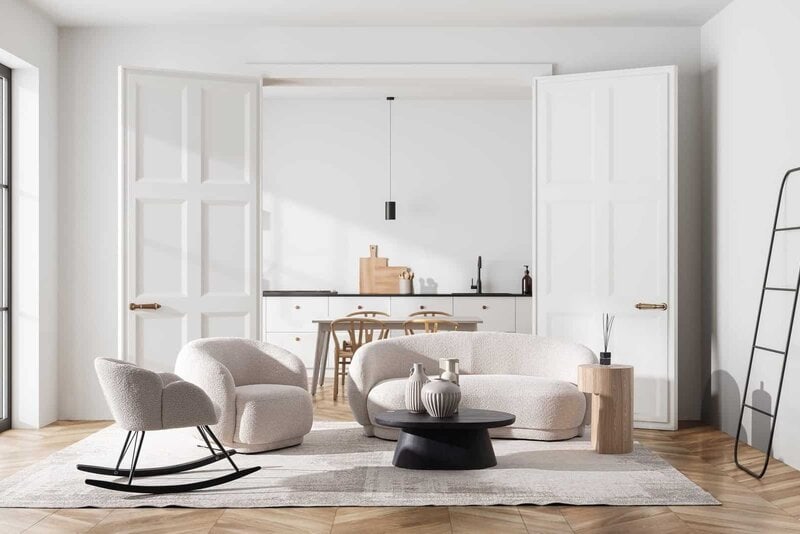 Soggiorno elegante con divani bianchi e arredi moderni, luce naturale e atmosfera accogliente in stile scandinavo.