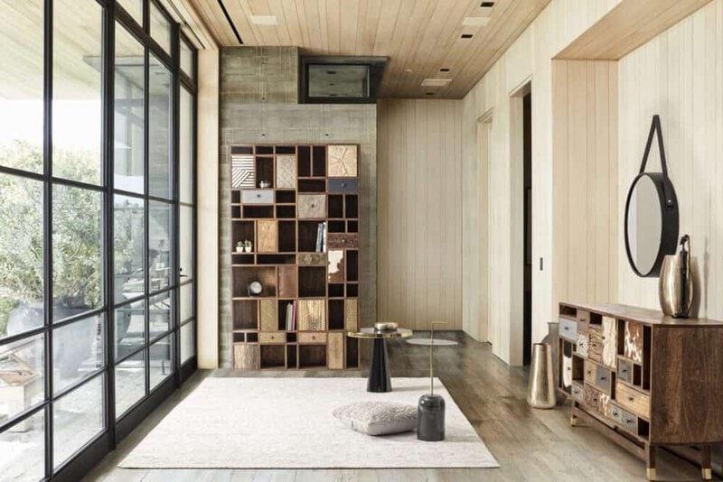 Ampio soggiorno con pareti in legno, libreria decorativa e grande finestra panoramica.