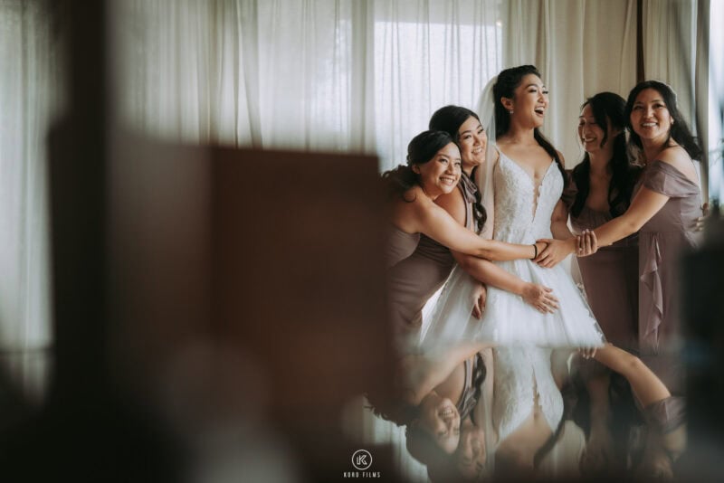 The bride laughs with her bridesmaids in dusty-pink dresses as she gets ready at The Ritz-Carlton, Koh Samui