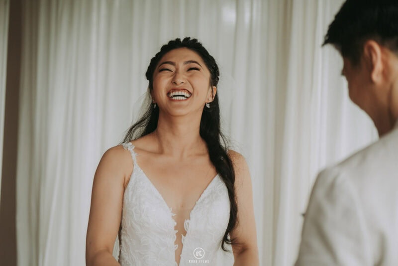 The bride smiles at the groom in his beige suit before their ceremony at The Ritz-Carlton, Koh Samui