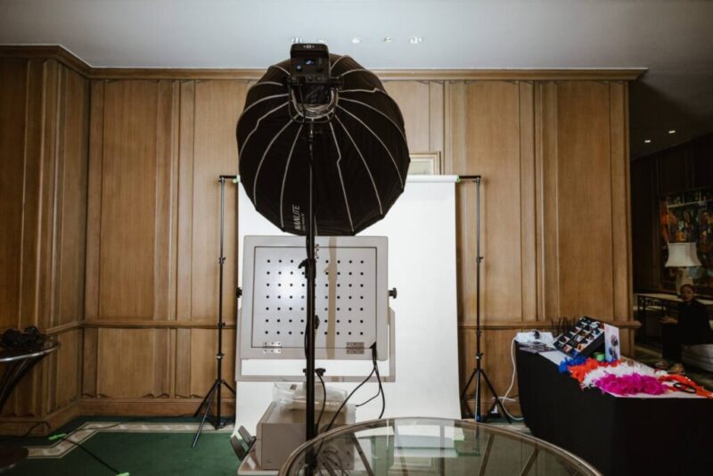 Studio photo booth corner in a hotel function room with softbox light, backdrop and props