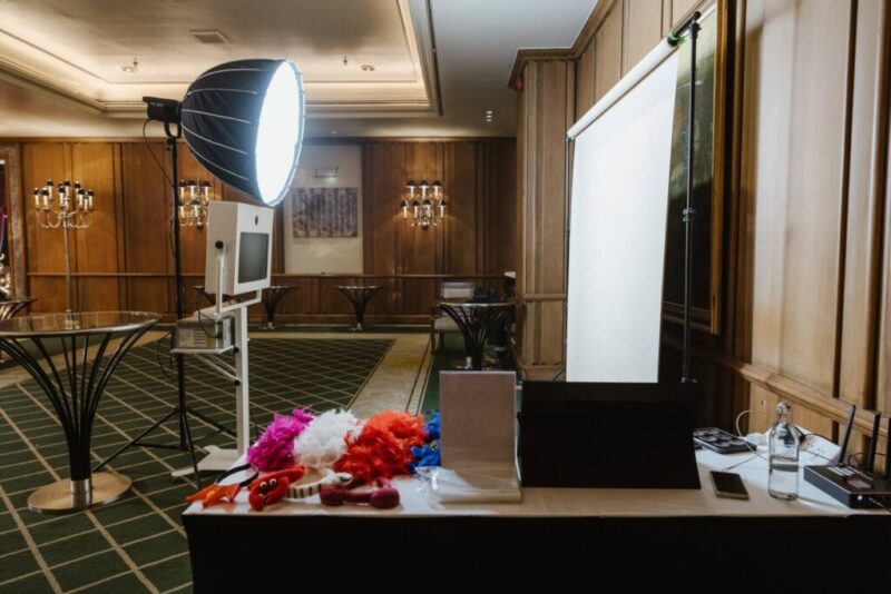 Studio booth in a hotel ballroom: softbox light, camera kiosk, white backdrop and props table
