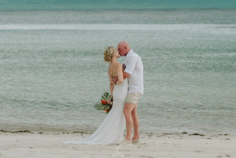 Amanda and Rob kiss at the water’s edge on the beach at Baan Puri, Koh Samui
