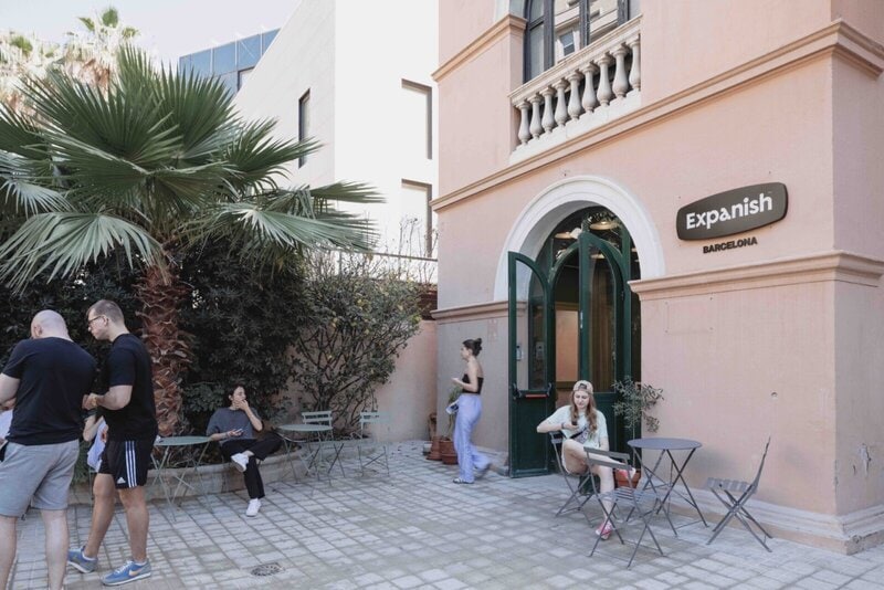 Außenbereich der Expanish-Sprachschule in Barcelona mit entspannter Atmosphäre, Palmen und Studierenden im Hof.