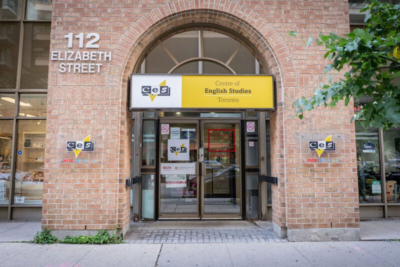 Eingang des Centre of English Studies (CES) in Toronto, mit gelbem Schild und Backsteinfassade.