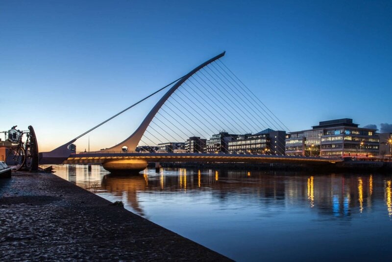 Die Samuel Beckett Bridge in Dublin bei Sonnenuntergang, reflektiert im ruhigen Wasser des Flusses Liffey.