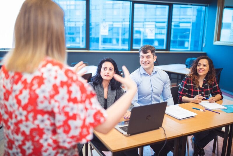 Erwachsene Teilnehmer in einer interaktiven Schulung oder einem Sprachkurs, während eine Lehrkraft spricht.