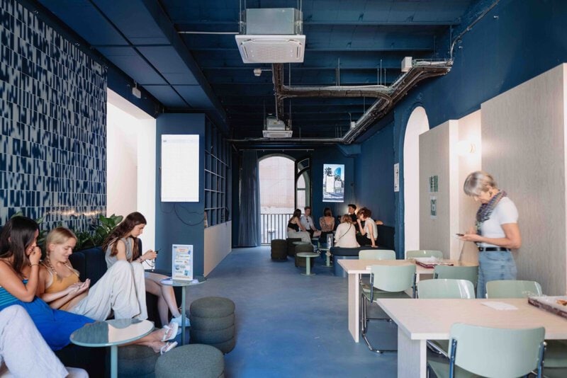 Moderner Aufenthaltsraum in der Expanish-Sprachschule Barcelona mit Studierenden in entspannter Atmosphäre.