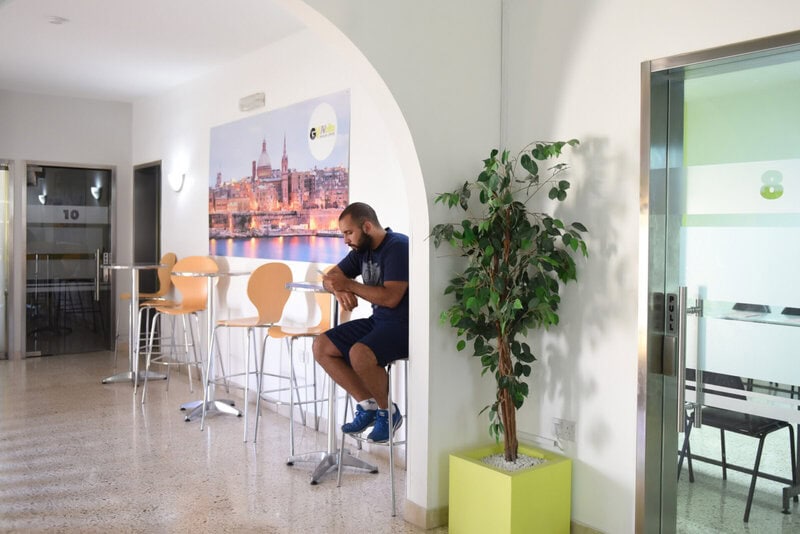 Moderner Aufenthaltsbereich in einer Sprachschule mit Sitzgelegenheiten und Wandbild von Valletta.