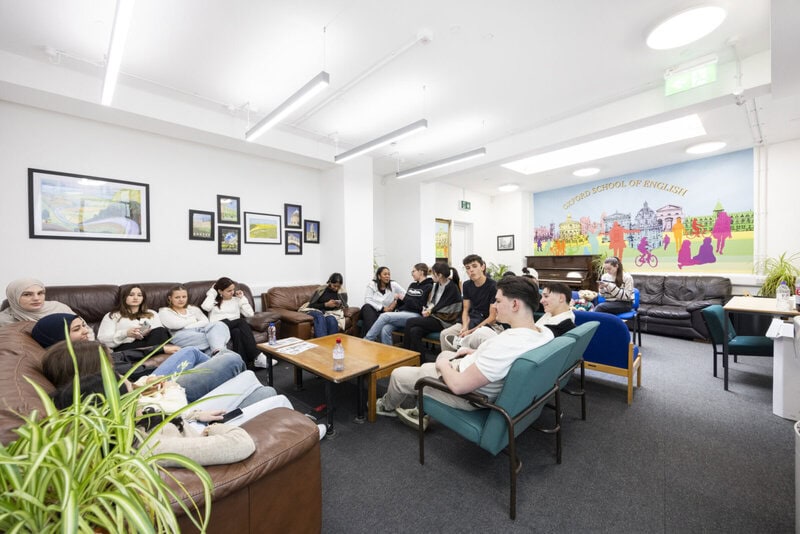 Gemeinschaftsraum der Oxford School of English mit internationalen Studierenden auf Sofas und Sesseln.