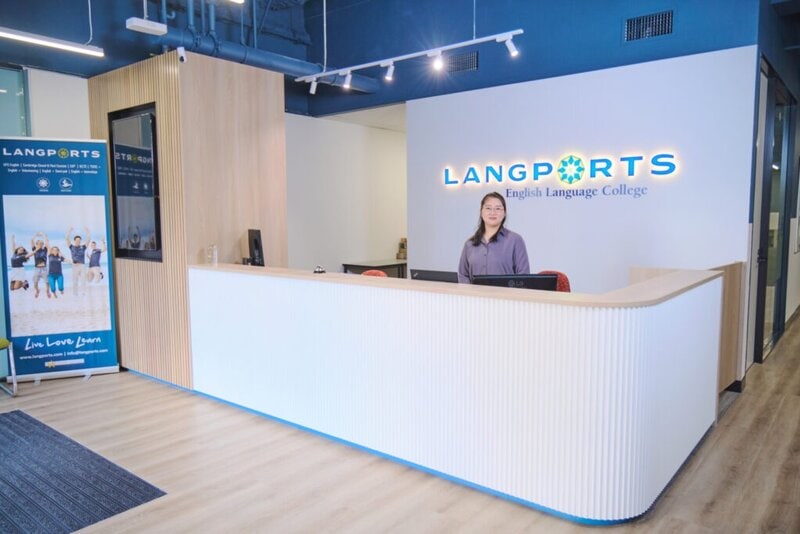 Empfangsbereich von Langports English Language College mit einer freundlichen Mitarbeiterin hinter dem modernen Empfangstresen.