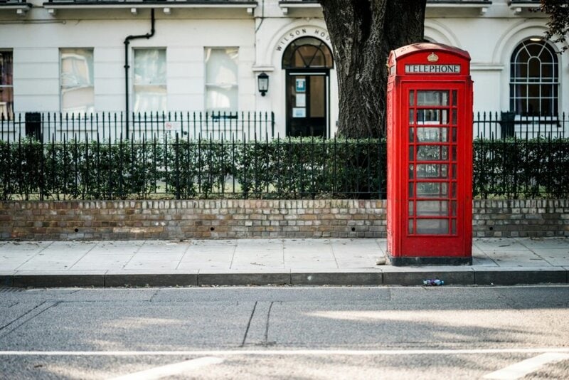 Klassische rote Telefonzelle in London vor einem historischen Gebäude.