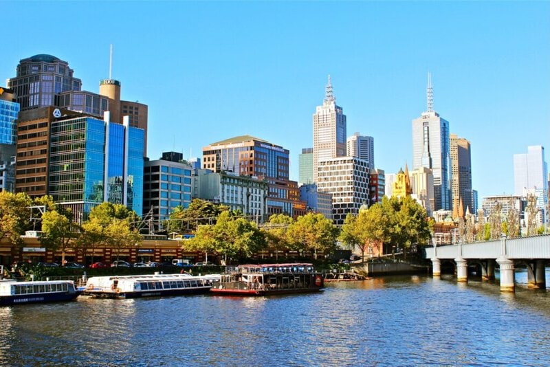 Skyline von Melbourne mit dem Yarra River und Ausflugsbooten an einem sonnigen Tag.