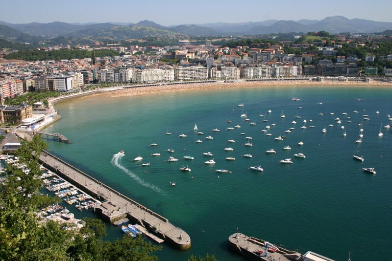 Luftaufnahme der Bucht La Concha in San Sebastián mit Sandstrand, Segelbooten und Stadtpanorama