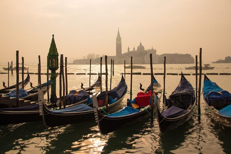 Gondeln in Venedig bei Sonnenuntergang mit Blick auf die Insel San Giorgio Maggiore und ihre beeindruckende Basilika.