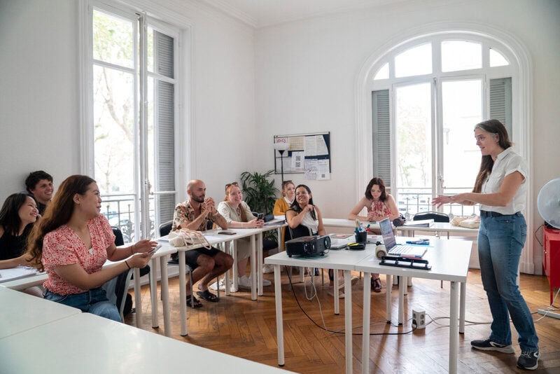 Interaktiver Sprachunterricht mit engagierter Lehrerin und motivierten Schülern in einem hellen Klassenzimmer.