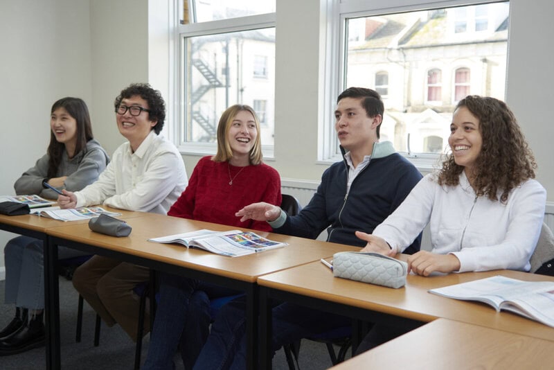 Lachende Sprachschüler in einem Klassenzimmer während einer interaktiven Unterrichtsstunde.