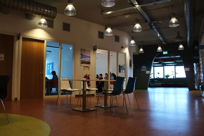 Moderner Aufenthaltsbereich in einer Sprachschule oder einem Bildungszentrum mit Lernräumen und Gruppenarbeit.