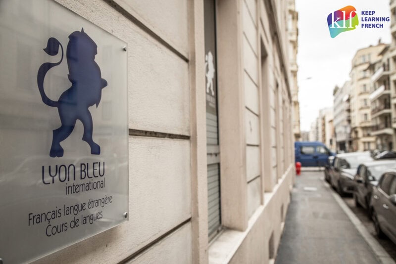 Eingang der Sprachschule Lyon Bleu International mit Logo-Schild an der Wand und Blick auf die Straße.