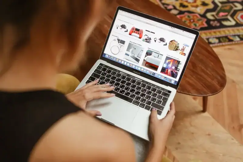 Person prüft Produktangebote und Informationen in einem Online-Shop auf einem Laptop.