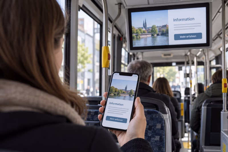 Fahrgast betrachtet im Bus eine digitale Information auf dem Smartphone, die gleichzeitig auf dem Fahrgast-TV angezeigt wird.
