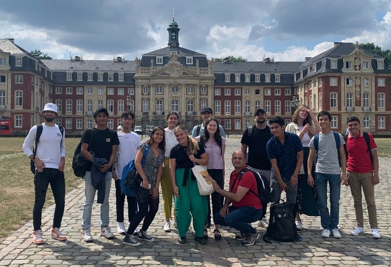 Internationale Studierendengruppe vor dem barocken Schloss Münster in Deutschland