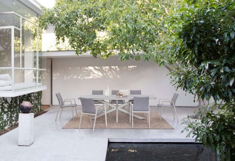 Tavolo da pranzo moderno all'aperto in un giardino elegante con piante rigogliose.