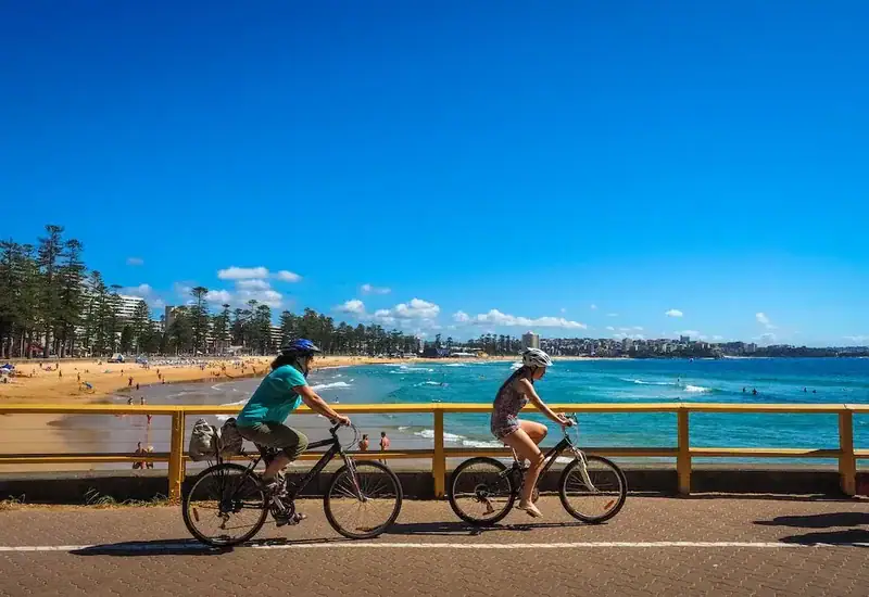 Zwei Radfahrer genießen eine Fahrt entlang der Küste mit Blick auf den Sandstrand und das blaue Meer.