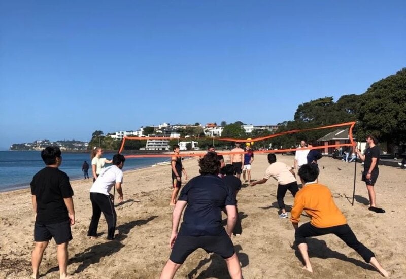 Sprachschüler spielen Beachvolleyball am sonnigen Strand