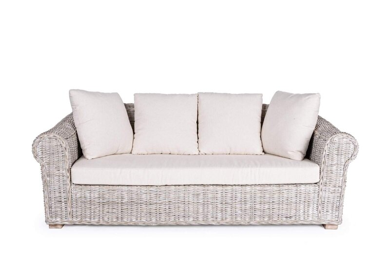 Divano in vimini bianco con cuscini morbidi, ideale per soggiorni e spazi outdoor di charme.