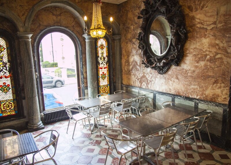 Historisches Café mit Marmordekor, Buntglasfenstern und Kronleuchter.