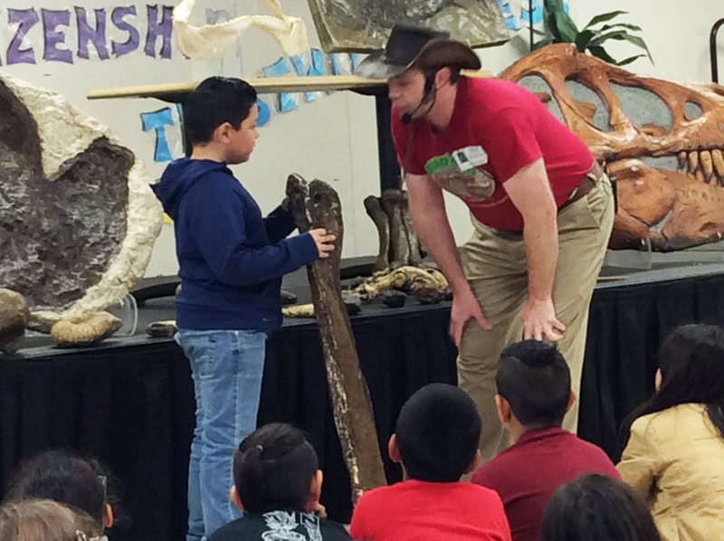 Dinosaurs Rock School Assembly in California Dinosaurs Rock Instructor having student hold a dinosaur bone during a Dinosaurs Rock School Assembly