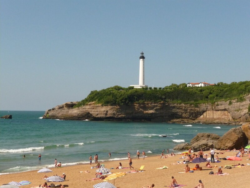 Strand von Biarritz mit dem Leuchtturm Phare de Biarritz auf den Klippen im Hintergrund.