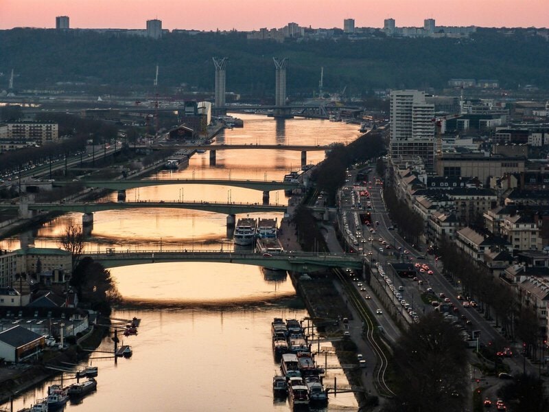 Stadtansicht mit mehreren Brücken über einen Fluss bei Sonnenuntergang.