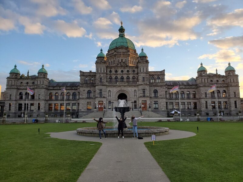 Das Parlamentsgebäude von British Columbia bei Sonnenuntergang mit Brunnen und Besuchern auf dem Vorplatz.