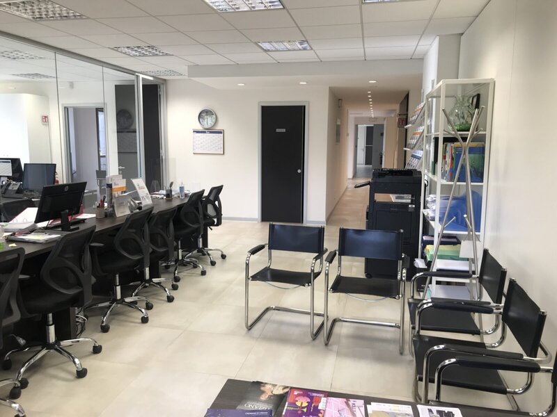 Modernes Büro mit Empfangsbereich, Wartebereich und Arbeitsplätzen mit Computern.