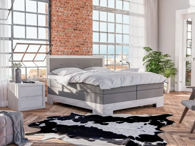 Boxspring postelja Tristan v sivi barvi z lesenim podnožjem v svetlem industrijskem ambientu
