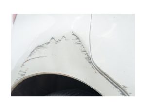 a white car with a big dent in its side indicating a quick car dent repair