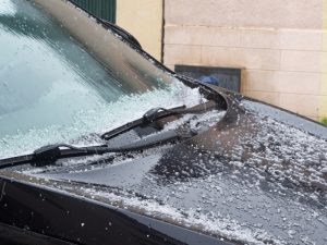 Car covered in hail and snow highlighting the need for small dent auto repair.